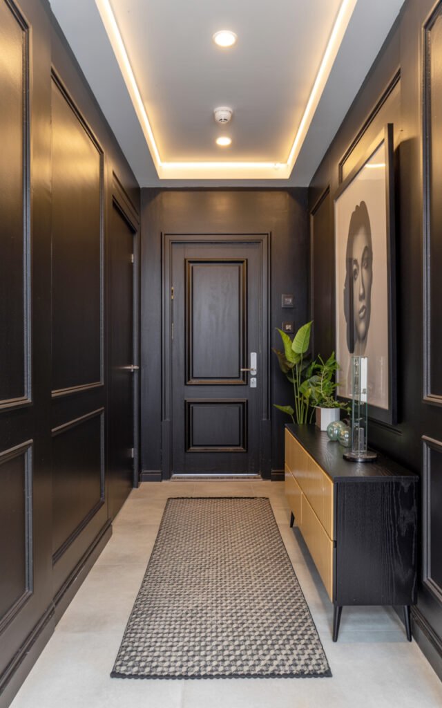 Fully styled black and white small entryway showing walls lighting console art and geometric rug together