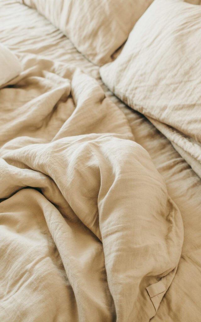 Close-up of textured linen bedding in natural tones showing quality material and inviting appearance