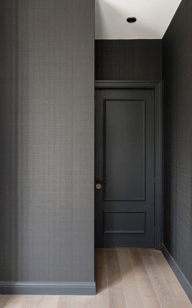 Textured black grasscloth wallpaper creating dimensional sophisticated wall treatment in entryway