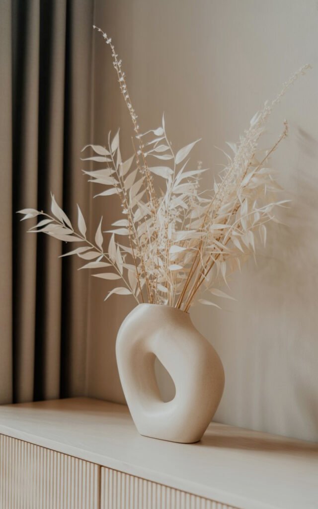 Neutral dried stems in organic white vase adding natural texture to entryway styling