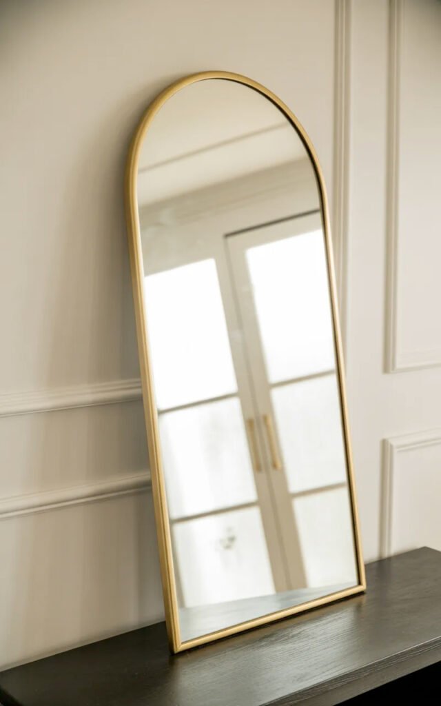 Classic arched mirror with brass frame adding elegance above hallway console