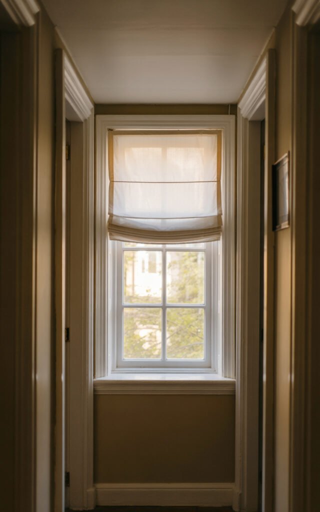 Window with white trim at hallway end bringing natural daylight into narrow corridor space