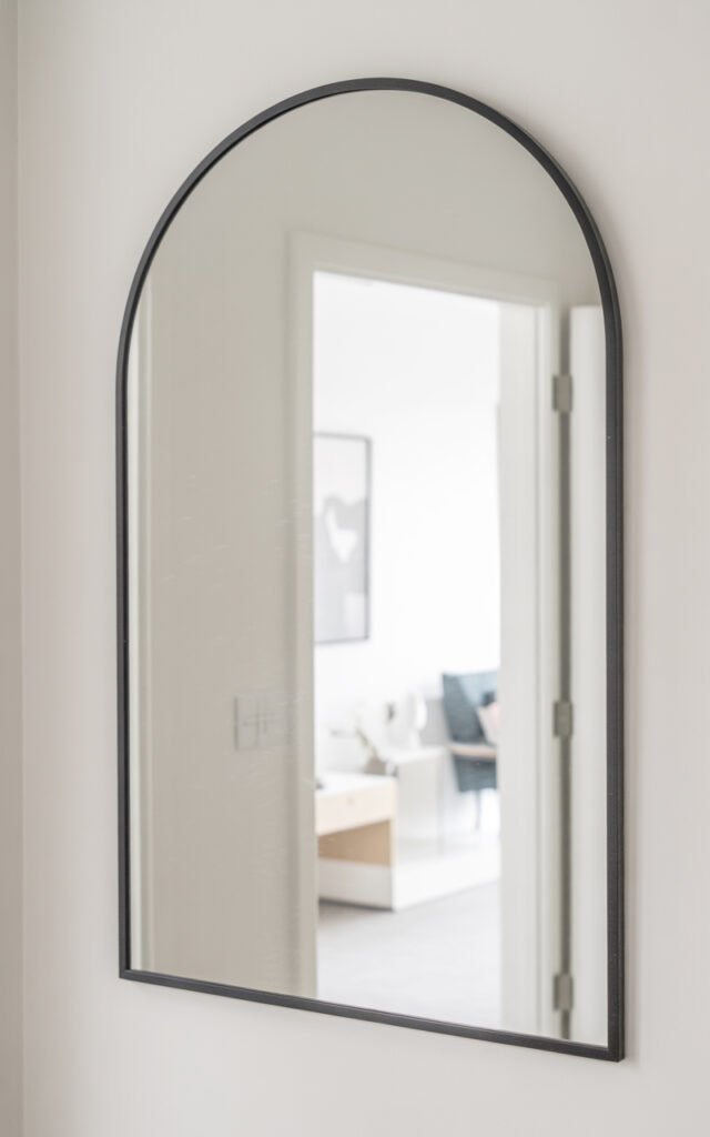 Oversized arched mirror with minimal frame creating focal point in hallway entrance