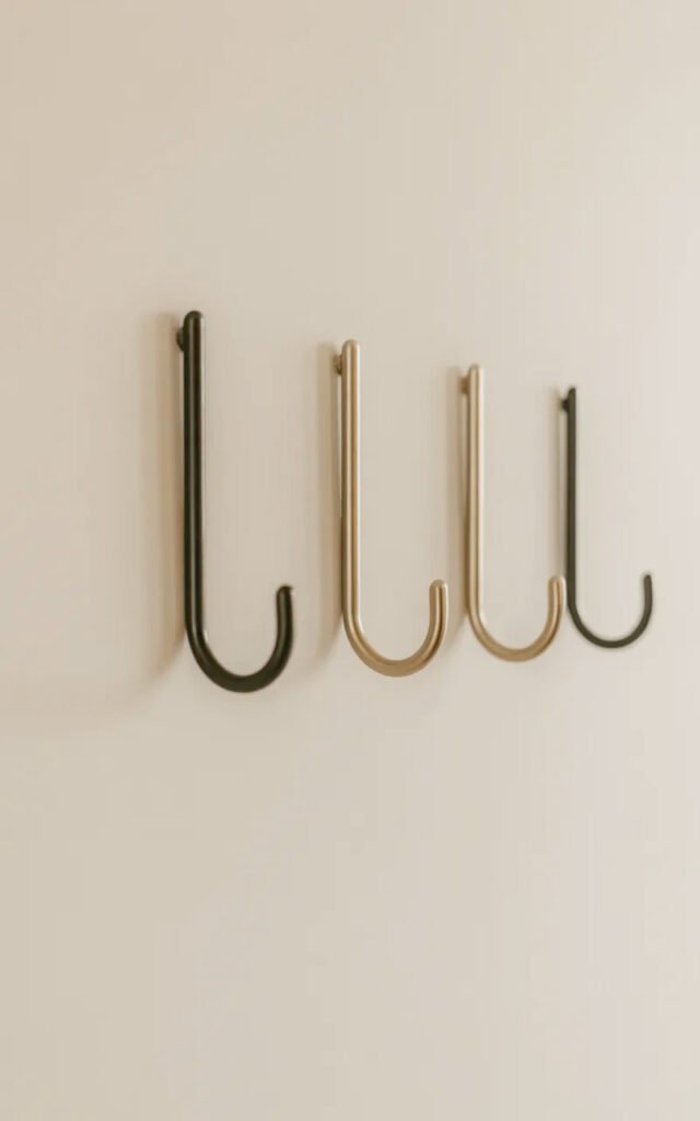 Minimal wall hooks in black providing coat and bag storage in tiny entrance