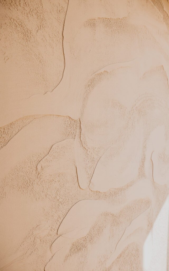 DIY textured wall treatment in warm beige showing organic plaster finish for earthy bedroom design