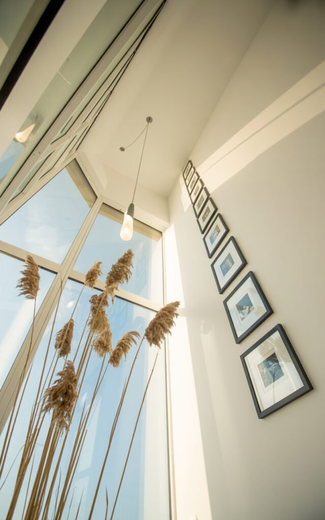 Bedroom showing vertical design elements including hanging pendant light, tall pampas grass, and high gallery wall creating sense of height and space