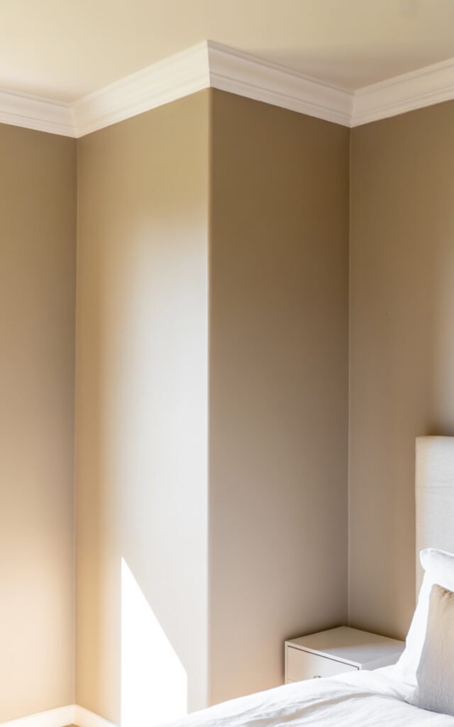 Warm neutral greige wall paint creating cozy elegant atmosphere in compact master bedroom