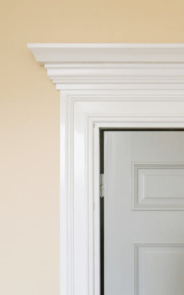 Crisp white door frame and molding providing clean contrast in neutral entryway