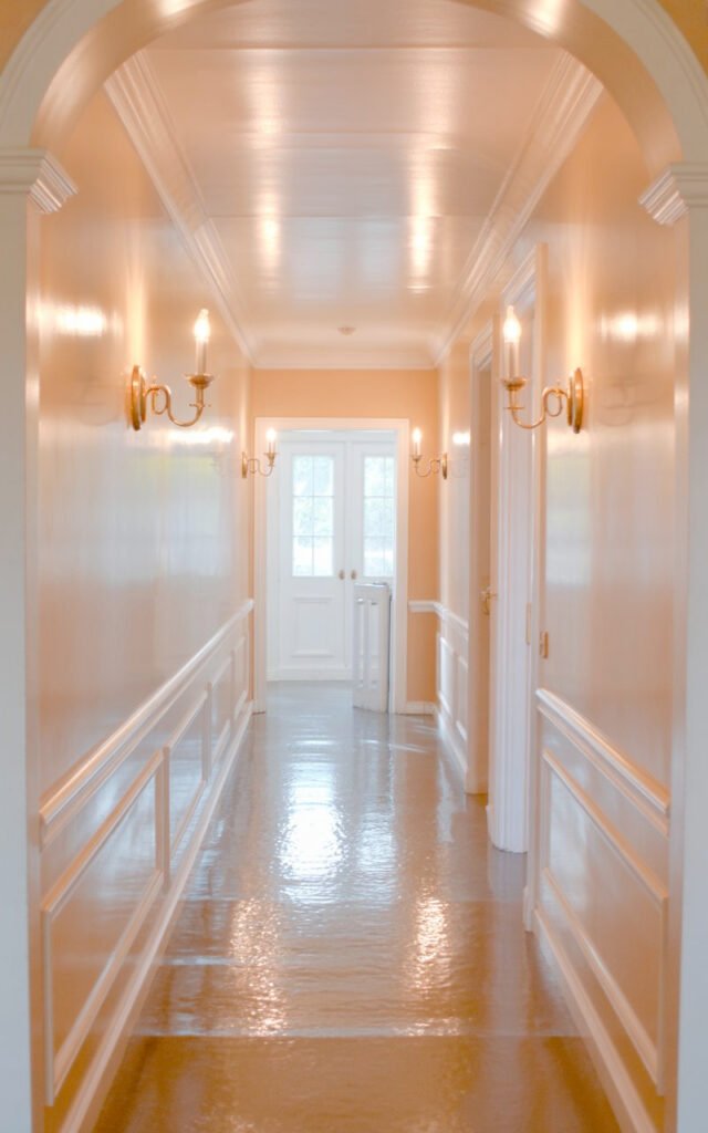 Light neutral wall color in white or cream reflecting lighting beautifully in hallway